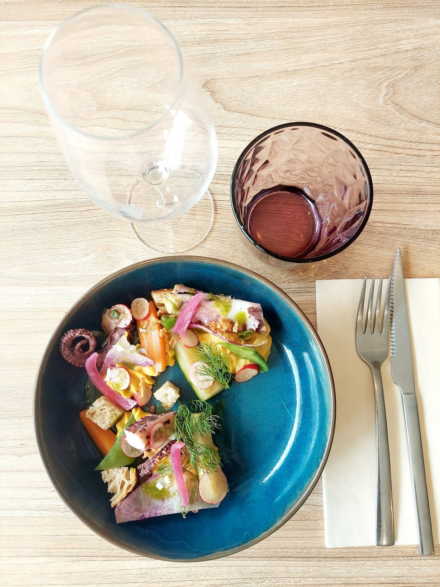 Entrée colorée servie sur une assiette bleue d'un potier du village