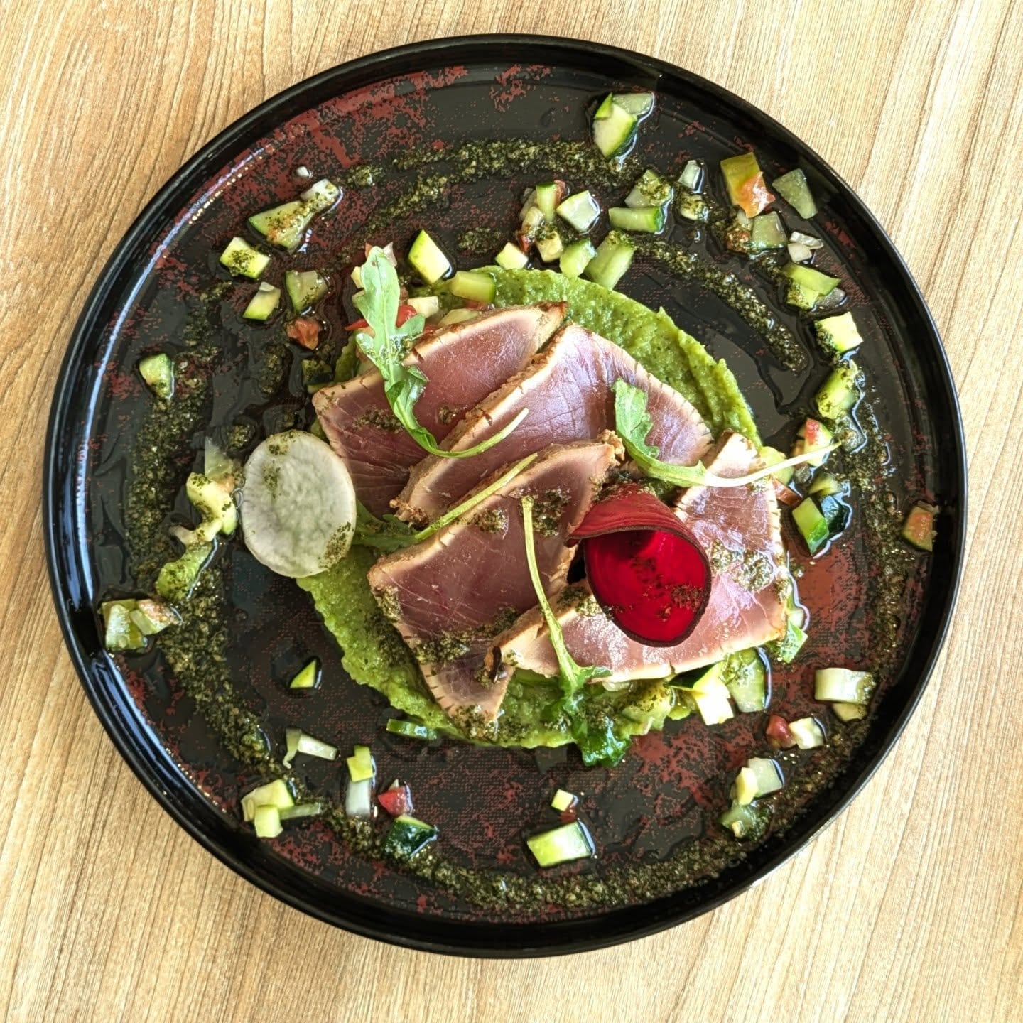 Thon mi-cuit, condiments et herbes fraîches sur assiette de grès noir